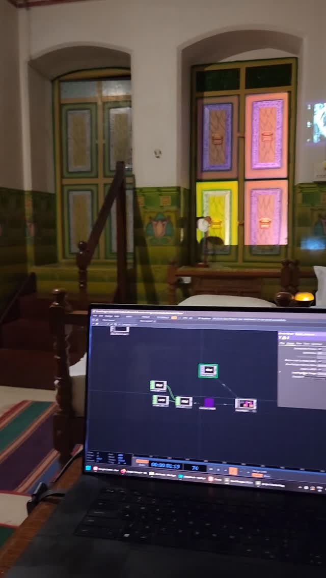 Colour projected onto carved doors of a Chettinad mansion, a laptop running TouchDesigner in front