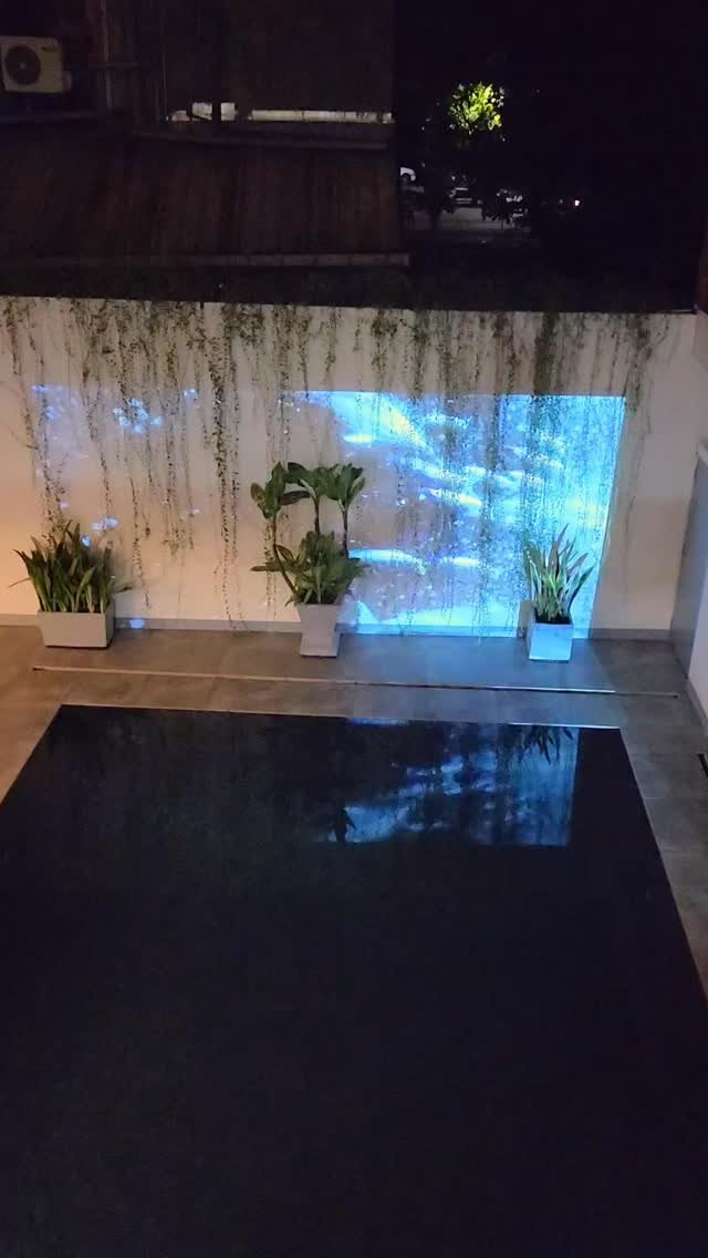 Blue projected shapes on a courtyard wall by a pool
