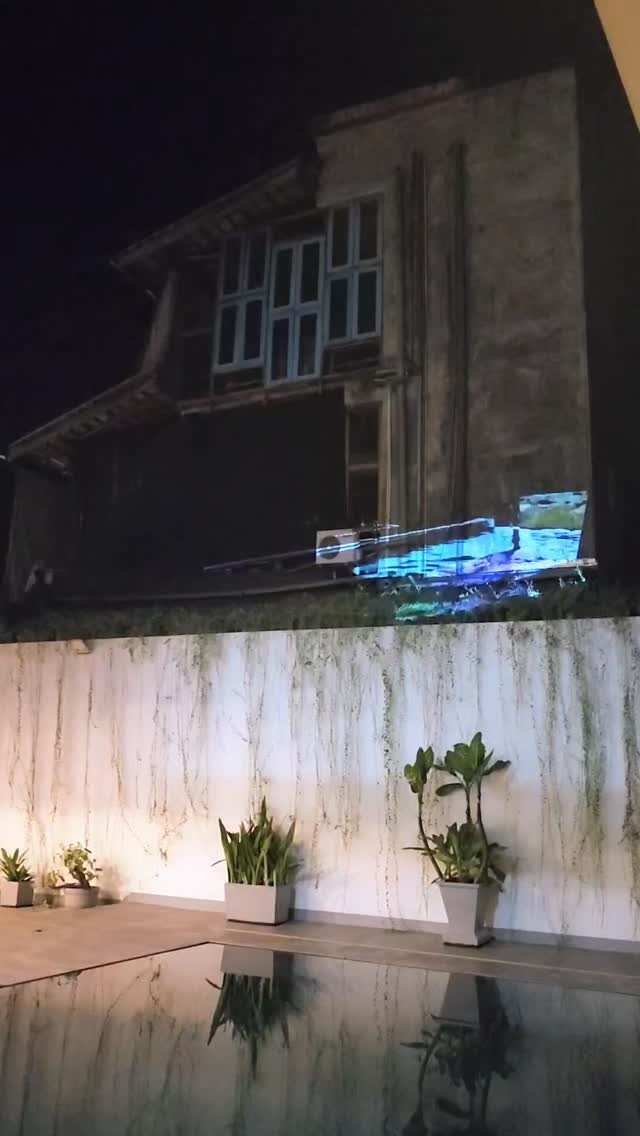 Projected light on a villa wall above a pool at night
